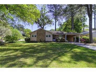 Charming single-story home boasts a lush green lawn, mature trees, and a convenient attached carport at 1629 Anita Ne Pl, Atlanta, GA 30306