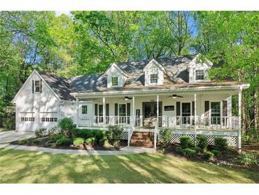 Charming home exterior featuring a welcoming front porch, well-manicured lawn and beautiful, mature trees at 2100 Kings Valley Dr, Lawrenceville, GA 30043