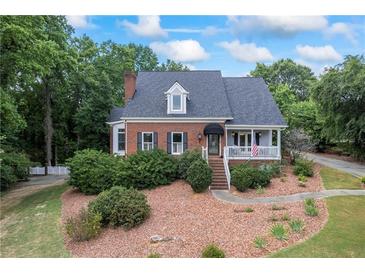 Charming brick home featuring a landscaped front yard and inviting front porch, perfect for relaxing outdoors at 2610 Ginger Dr, Buford, GA 30519