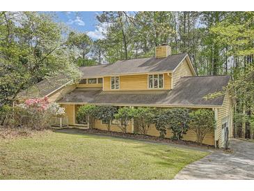 Charming two-story yellow home with mature trees and an inviting landscaped yard at 103 Nob Hl, Peachtree City, GA 30269