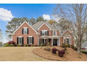 Charming two-story brick home featuring black shutters, mature trees, and a well-manicured lawn, perfect for suburban living at 214 Cedar Woods Way, Canton, GA 30114