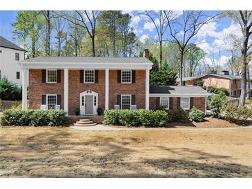 Beautiful brick home featuring a symmetrical design, white columns, and manicured landscaping at 495 Heritage Way, Atlanta, GA 30328