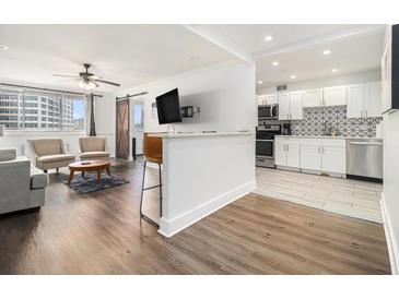 Inviting living room featuring hardwood floors, ceiling fan, and a breakfast bar open to the kitchen at 215 Piedmont Ne Ave # 708, Atlanta, GA 30308