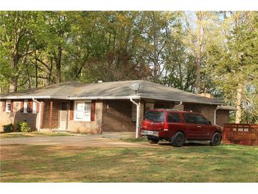 Quaint brick home with a mature lawn, featuring a driveway and a red SUV parked in front at 1185 Highway 162, Covington, GA 30016