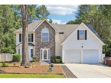 Charming two-story home featuring a stone facade, white siding, a two-car garage, and a well-maintained front yard at 277 Edison Dr, Stockbridge, GA 30281