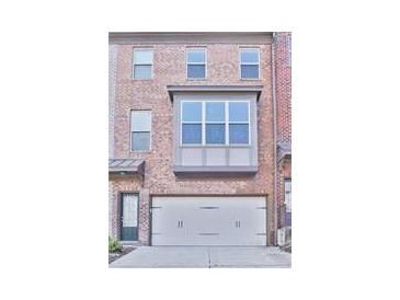 Charming brick townhome featuring an attached garage and inviting front entrance at 1147 Laurel Valley Ct, Buford, GA 30519