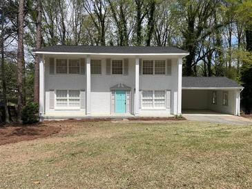 Charming two-story brick home with a light blue front door and a covered carport on a wooded lot at 3467 Valley Ridge Sw Ter, Atlanta, GA 30331
