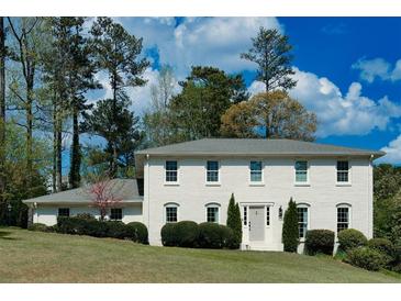 Charming white brick home with manicured landscaping and a lush green lawn at 3811 Valley Green Dr, Marietta, GA 30068