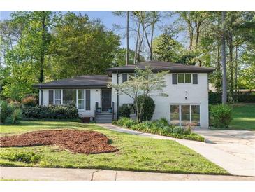 Charming two-story brick home featuring landscaped yard, fresh green grass, and mature trees at 2315 Shamrock Dr, Decatur, GA 30032