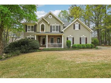 Charming two-story home with stone accents and a well-manicured front lawn and mature trees at 3997 Ironhill Ln, Woodstock, GA 30189
