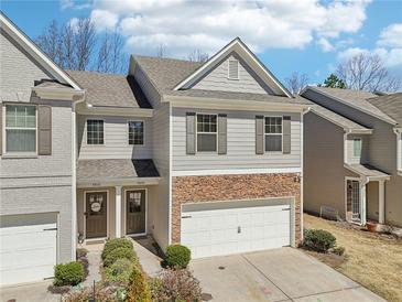 Charming townhome with stone accents, a two-car garage, and well-maintained landscaping at 5890 Vinyard Ln, Cumming, GA 30041