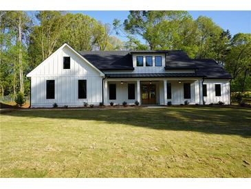 Beautiful white farmhouse with black trim, covered porch, and a large front yard at 1632 Oleander Sw Dr, Lilburn, GA 30047