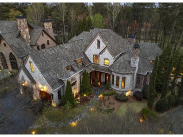 Stunning exterior elevation of stone home with turret, manicured landscaping and mature trees at 290 Ardsley Ln, Alpharetta, GA 30005