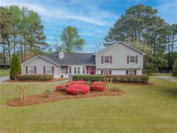 Charming home featuring beautiful landscaping and a well-manicured lawn in a serene, tree-lined neighborhood at 1717 Ramblewood Way, Snellville, GA 30078