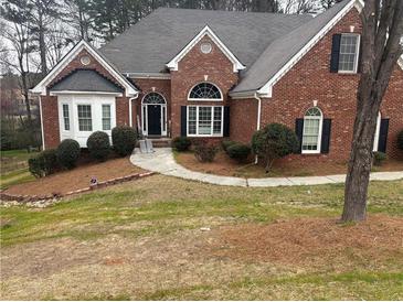 Charming brick home featuring a well-manicured lawn, arched windows, and a welcoming front entrance at 3570 Bulloch Lake Rd, Loganville, GA 30052