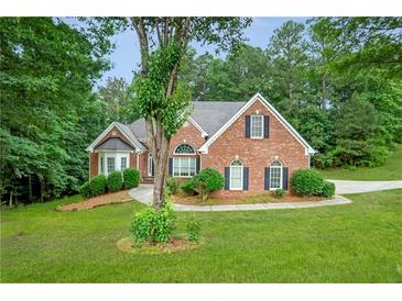 Charming brick home with well-manicured lawn and mature trees, showcasing curb appeal at 3570 Bulloch Lake Rd, Loganville, GA 30052