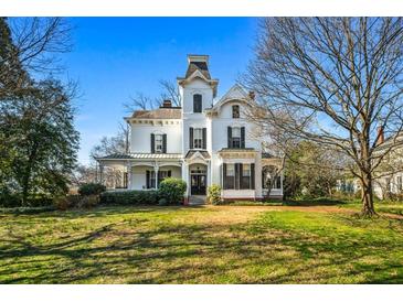 A grand, white Victorian home with a tower, black shutters, and a spacious green lawn in the front yard at 285 Kennesaw Nw Ave, Marietta, GA 30060