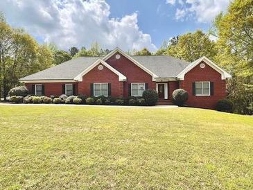 Beautifully landscaped red brick home with a well-manicured lawn and lush trees at 512 Clearwater Dr, Mcdonough, GA 30252