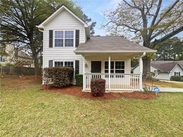 Charming two-story home with landscaped yard, inviting front porch, and classic architectural details at 7747 Rountree Xing, Riverdale, GA 30274