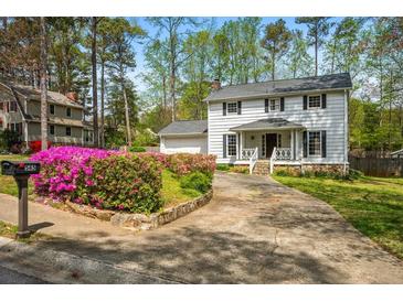 Charming two-story home with white siding, black shutters, and a beautifully landscaped front yard with colorful flowers at 545 Bellemeade Sw Dr, Marietta, GA 30008