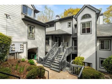 View of townhouse with multiple stories, gray siding, and stairs leading to front entrance at 8207 Fairview Blf, Alpharetta, GA 30022