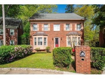 Charming two-story brick home featuring a landscaped front yard and a vibrant red front door at 3100 Queens Ne Walk, Atlanta, GA 30345