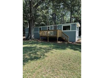 Inviting single-story home featuring a wood deck, a gray exterior, and mature trees at 5400 Kings Camp Rd, Acworth, GA 30102