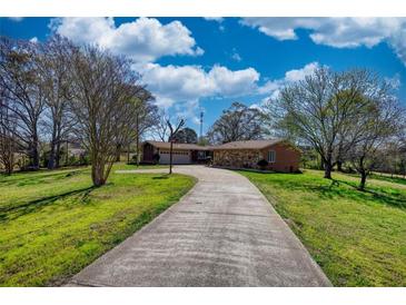 Charming single-story home with a long driveway and well-maintained landscaping, under a bright, partly cloudy sky at 610 Loth Wages Rd, Dacula, GA 30019