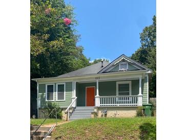 Charming home featuring a cozy front porch, orange front door and verdant lawn at 693 Dill Sw Ave, Atlanta, GA 30310