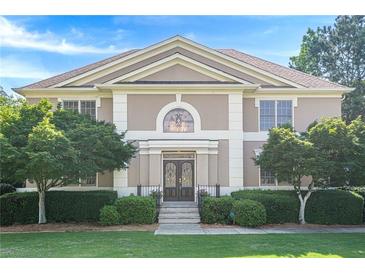 Elegant two-story home with a symmetrical facade, manicured lawn, and mature landscaping at 7415 Northampton Ct, Cumming, GA 30040