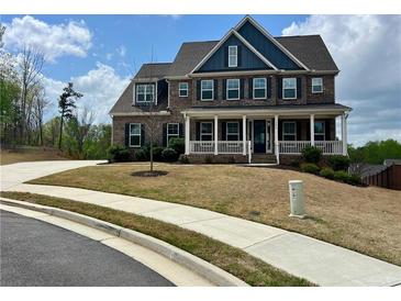 Charming two-story brick home featuring a welcoming front porch and manicured lawn at 5458 Summer Pine Pl, Buford, GA 30518
