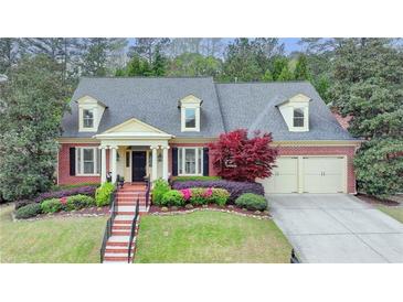 Charming brick home featuring manicured landscaping, dormer windows and a two-car garage at 8070 Georgetown Cir, Suwanee, GA 30024