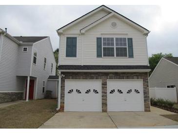 Two-story home featuring a two-car garage, a brick foundation, and light gray siding at 5815 Mountain Top Pl, Cumming, GA 30041