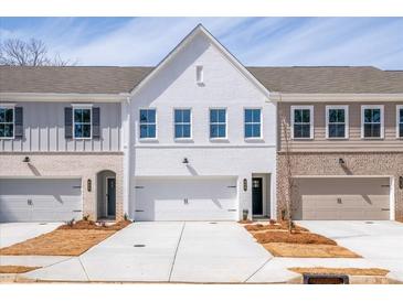 Charming townhome showcasing a white brick facade, attached garage, and manicured lawn at 409 Carrera Ln, Acworth, GA 30102