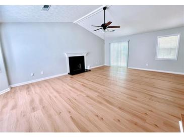 Open living room with vaulted ceilings, fan, fireplace, hardwood floors, and natural light at 440 Sheppard Xing Ct, Stone Mountain, GA 30083
