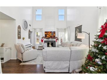 Cozy living room featuring soaring ceilings, a fireplace, and comfortable seating with a view to the backyard at 1240 Birchwood Ln, Roswell, GA 30076