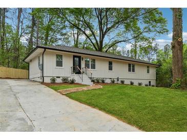 Charming single-story home featuring a black front door, well-kept lawn, and a concrete driveway at 1232 Andrews Dr, Marietta, GA 30062