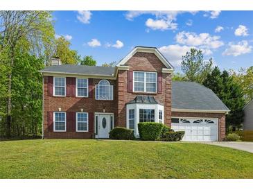 Two-story brick home with a well-manicured lawn, red shutters, and attached two car garage at 3937 Sautee Trl, Conley, GA 30288