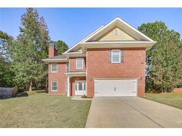 Charming two-story brick home with a well-manicured lawn, a two-car garage, and mature trees at 4066 Wild Orchid Ln, Loganville, GA 30052