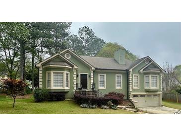 Charming green home with a well-maintained lawn and inviting front entrance with a bay window and attached garage at 2514 Green Forest Ct, Snellville, GA 30078
