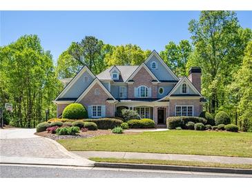 Beautiful two-story brick home with lush landscaping and a well-manicured lawn on a sunny day at 225 Ansley Close, Roswell, GA 30075