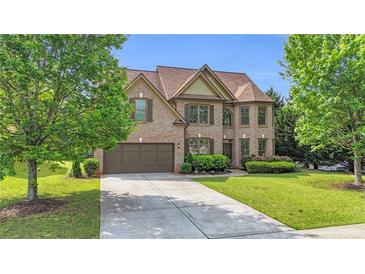 Charming brick two-story home with a well-manicured lawn, mature trees, and a two-car garage at 2369 Apalachee Crucis Ln, Dacula, GA 30019