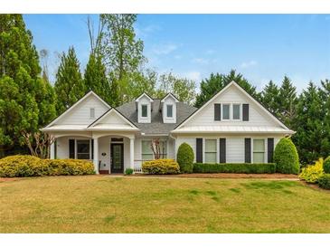 Charming white home featuring a well-manicured lawn and inviting landscaping with mature trees at 133 Newcastle Walk, Woodstock, GA 30188