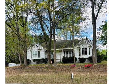Charming white home featuring well-maintained landscaping and a welcoming covered front porch at 30 Dogwood Trl, Dallas, GA 30157