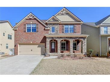 Beautiful two-story brick home with a stone porch and arched entryways at 7130 Rocking Horse Ln, Cumming, GA 30040