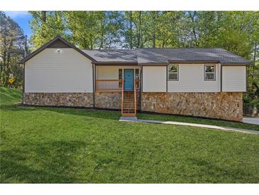 Charming home with a stone foundation, a bright blue front door, and a lush green lawn at 4718 Lou Ivy Rd, Peachtree Corners, GA 30096