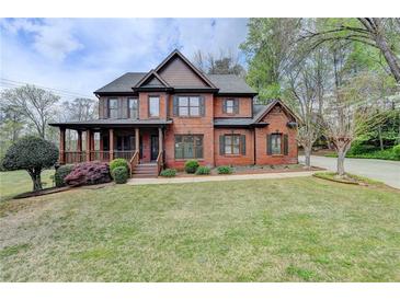 Stately two-story brick home featuring a covered front porch and mature landscaping at 220 Carriage Station Dr, Lawrenceville, GA 30046