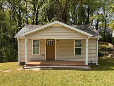 Charming single-story home featuring a cozy front porch, neutral siding, and lush greenery at 1938 Main Nw St, Atlanta, GA 30318