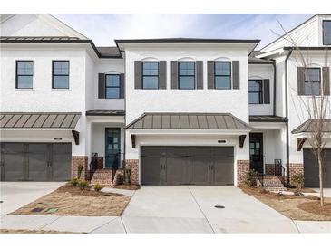 Charming new construction townhomes featuring white brick, metal roof accents, and convenient garage parking at 702 Dodd Ln # 159, Buford, GA 30518