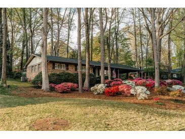 Charming single-story brick home featuring a well-manicured lawn and colorful azalea bushes in a beautiful landscape at 2744 Hunting Hill Ln, Decatur, GA 30033